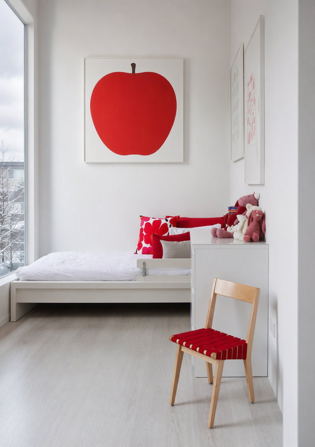 A minimalist modern children's bedroom with a bright white color scheme, featuring a low-profile white bed with a red patterned pillow, a wooden chair — toddler bedroom ideas reference 1
