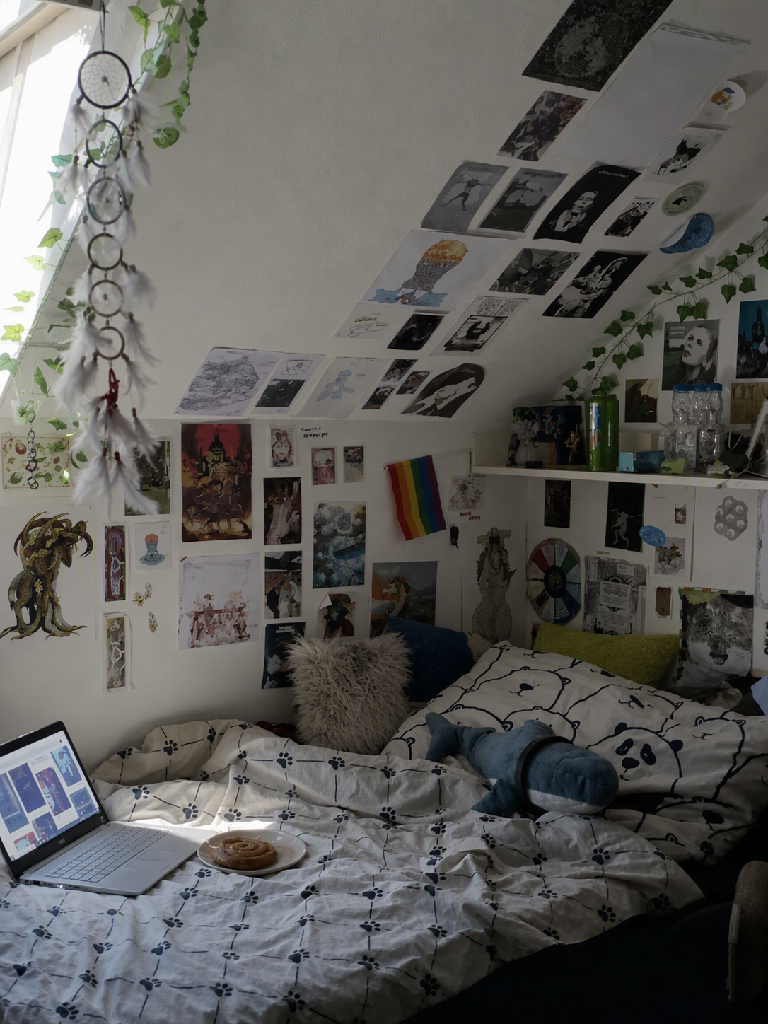 A cozy, personalized bedroom with a sloped ceiling, featuring a bed covered in a white duvet with black paw print patterns and a panda-themed pillow — attic bedroom ideas reference 4